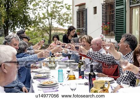 Stock Photograph - Family toasting at outdoor lunch in garden, Florence, Italy. Fotosearch