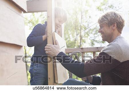 Picture - Father and son building treehouse together in garden. Fotosearch