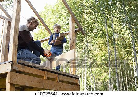 Father and son building treehouse together in garden View Large Photo Image Stock Image - Father and son building treehouse together in garden. Fotosearch
