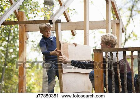 Father and son building treehouse together in garden View Large Photo Image Stock Image - Father and son building treehouse together in garden. Fotosearch