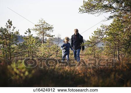 Stock Image - Father and son exploring forest, Finland. Fotosearch