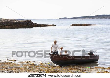Picture - Father and sons playing beside boat moored on beach, Norway. Fotosearch