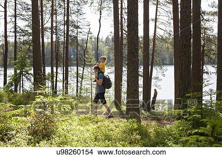 Picture - Father giving son piggyback ride in forest, Finland. Fotosearch
