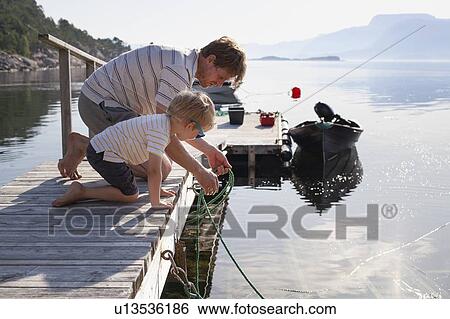 Stock Photograph - Father teaching son to tie boat to pier, Norway. Fotosearch