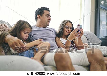 Father watching daughters play computer games on cellphone View Large Photo Image Stock Image - Father watching daughters play computer games on cellphone. Fotosearch