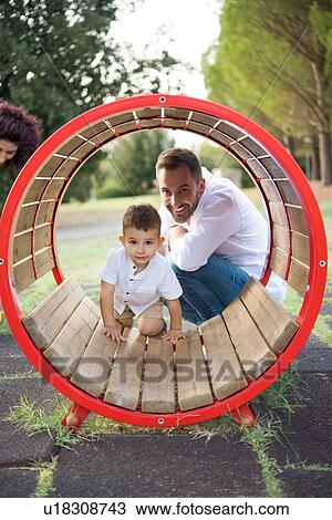 Father watching son playing in circular swing in park View Large Photo Image Stock Image - Father watching son playing in circular swing in park. Fotosearch