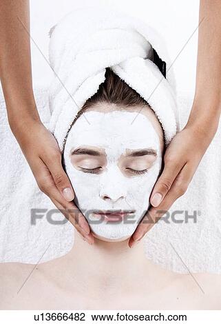 Stock Image - Female having face rub mask in spa. Fotosearch