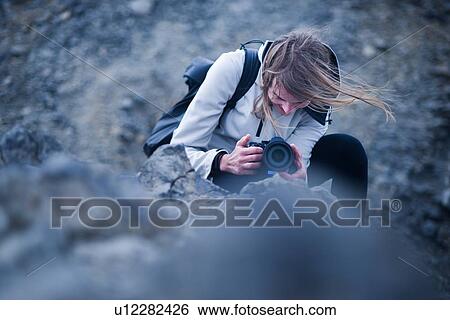 Stock Photograph - Female photographer kneeling to take photograph, Landmannalaugar, Iceland. Fotosearch