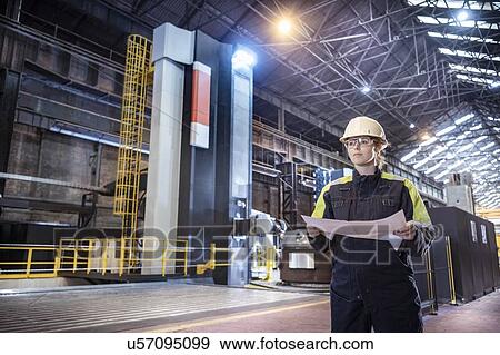 Stock Photo - Female worker with specialist large 3D cutting CNC lathe in steelworks. Fotosearch