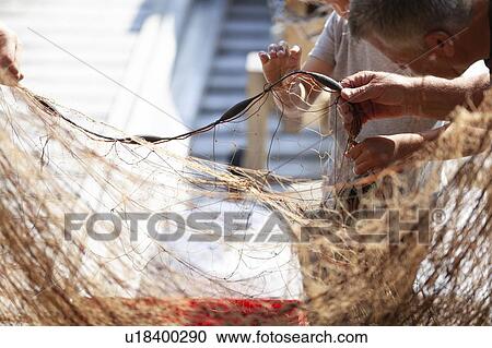 Fisherman and boy disentangling fishing net View Large Photo Image Stock Image - Fisherman and boy disentangling fishing net. Fotosearch