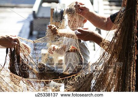 Stock Photo - Fisherman and boy disentangling fishing net. Fotosearch