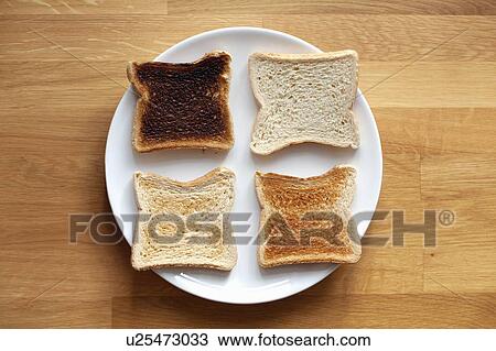 Stock Image - Four sliced bread on plate. Fresh, light toast, crispy toast and burnt. Fotosearch
