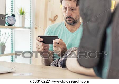 Stock Photo - Freelancer playing game on smartphone. Fotosearch