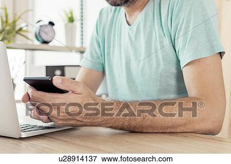Stock Photo - Freelancer using smart phone in home office. Fotosearch