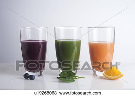 Stock Photo - Fresh juices made of berries, oranges and green leaves. Fotosearch