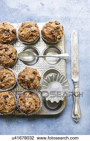 Stock Image - Freshly baked chocolate chip muffins on baking pan. Fotosearch