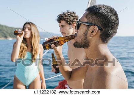 Stock Image - Friends enjoying beer on sailboat, Italy. Fotosearch
