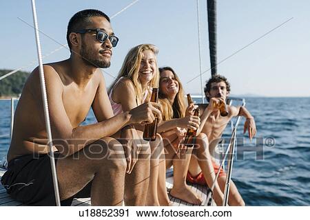 Stock Image - Friends enjoying beer on sailboat, Italy. Fotosearch