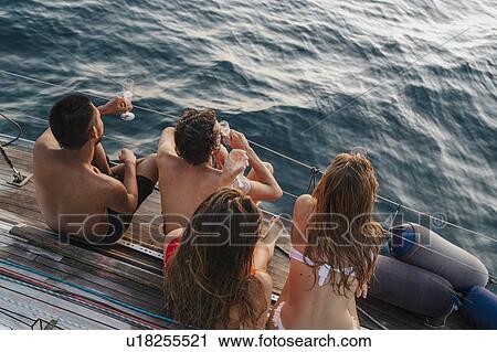 Stock Image - Friends enjoying champagne on sailboat, Italy. Fotosearch