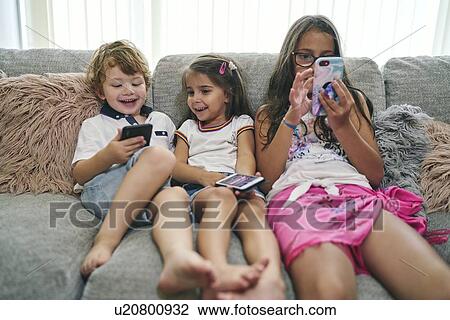 Friends enjoying computer games on sofa View Large Photo Image Stock Image - Friends enjoying computer games on sofa. Fotosearch