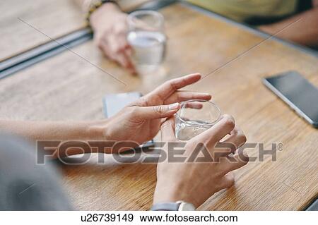 Stock Photo - Friends having water and talking in restaurant. Fotosearch