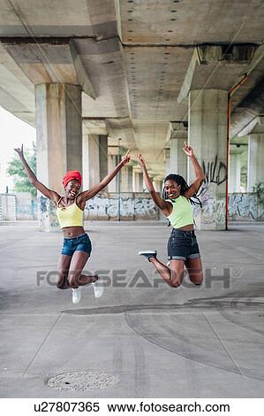Stock Photography - Friends jumping in mid air in city. Fotosearch