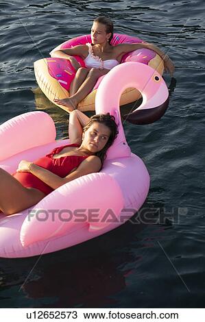 Stock Image - Friends on flamingo float on sea, Italy. Fotosearch