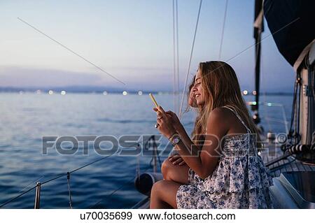 Friends on sailboat, sharing text message, Italy View Large Photo Image Stock Photo - Friends on sailboat, sharing text message, Italy. Fotosearch