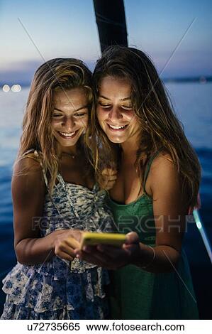 Friends on sailboat, sharing text message, Italy View Large Photo Image Stock Photography - Friends on sailboat, sharing text message, Italy. Fotosearch