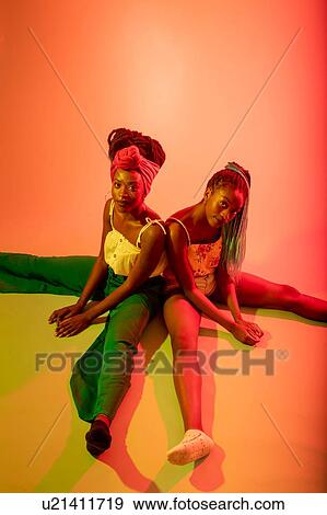 Stock Photo - Friends posing against orange background. Fotosearch
