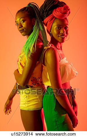 Friends posing back to back against orange background View Large Photo Image Picture - Friends posing back to back against orange background. Fotosearch