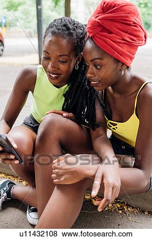 Stock Photo - Friends reading text message on smartphone in city. Fotosearch