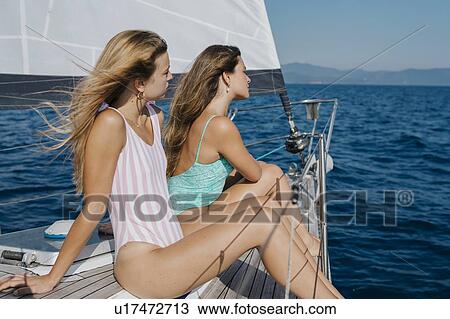 Stock Image - Friends relaxing on deck of sailboat, Italy. Fotosearch