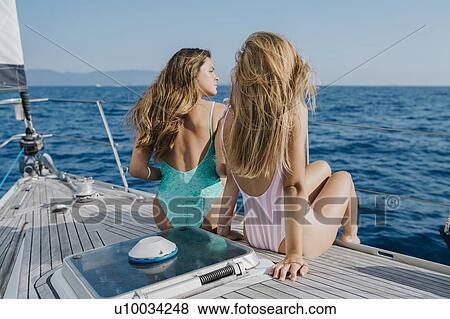 Stock Photo - Friends relaxing on deck of sailboat, Italy. Fotosearch