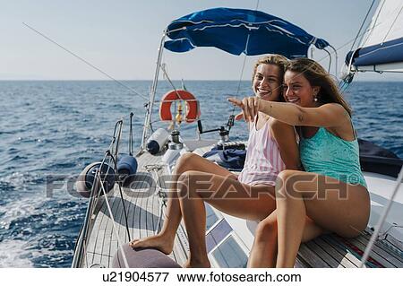Stock Photo - Friends relaxing on deck of sailboat, Italy. Fotosearch