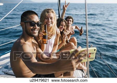 Stock Image - Friends taking selfie on sailboat, Italy. Fotosearch