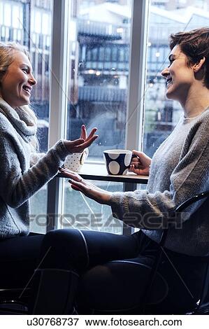 Stock Photo - Friends talking over tea in cafe. Fotosearch