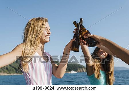 Picture - Friends toasting with beer on sailboat, Italy. Fotosearch