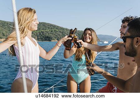 Stock Image - Friends toasting with beer on sailboat, Italy. Fotosearch