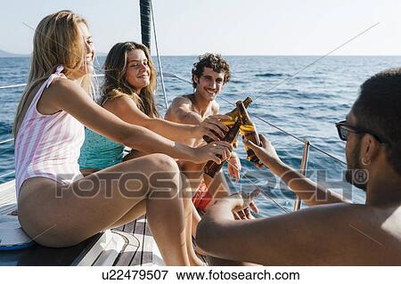 Friends toasting with beer on sailboat, Italy View Large Photo Image Stock Photo - Friends toasting with beer on sailboat, Italy. Fotosearch