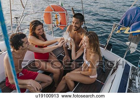 Stock Image - Friends toasting with champagne on sailboat, Italy. Fotosearch