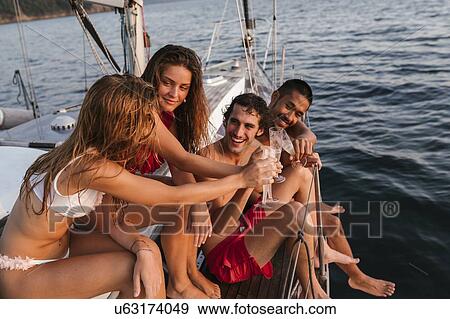 Stock Photo - Friends toasting with champagne on sailboat, Italy. Fotosearch