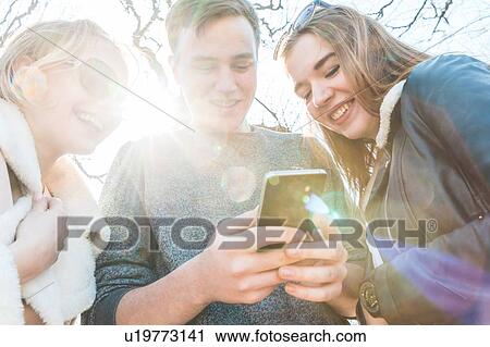 Stock Image - Friends using smartphone in city. Fotosearch