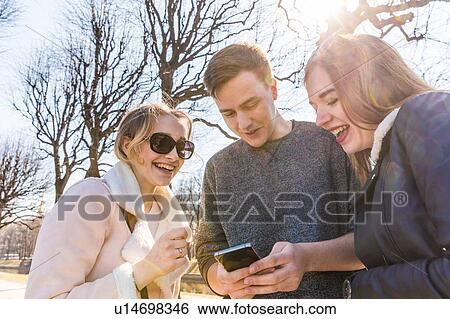 Stock Photograph - Friends using smartphone in city. Fotosearch