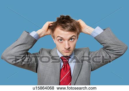 Stock Photo - Front view of young businessman in confusion scratching head. Fotosearch