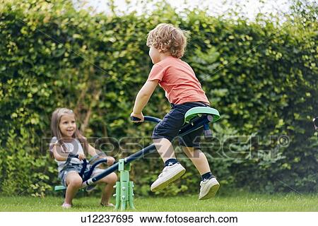 Girl and boy on toy seesaw in garden View Large Photo Image Stock Photography - Girl and boy on toy seesaw in garden. Fotosearch