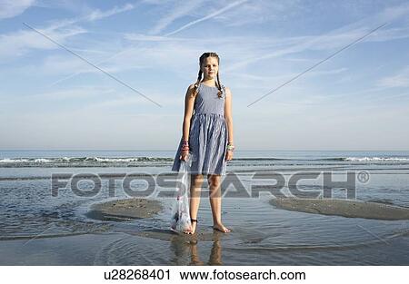 Stock Image - Girl collects plastic waste from beach, Hoek van Holland, Netherlands. Fotosearch