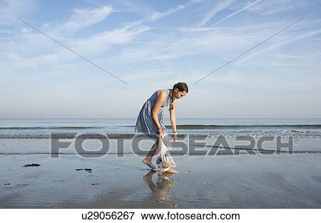 Stock Photo - Girl collects plastic waste from beach, Hoek van Holland, Netherlands. Fotosearch