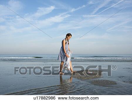Stock Photograph - Girl collects plastic waste from beach, Hoek van Holland, Netherlands. Fotosearch