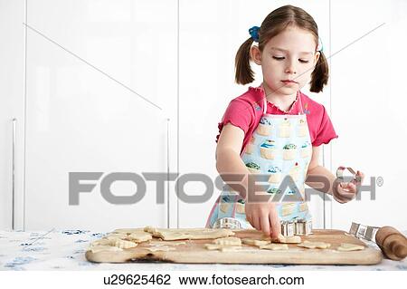 Girl cutting dough on board in kitchen View Large Photo Image Stock Image - Girl cutting dough on board in kitchen. Fotosearch